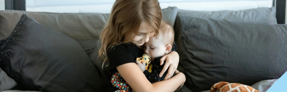 Große Schwester umarmt Baby